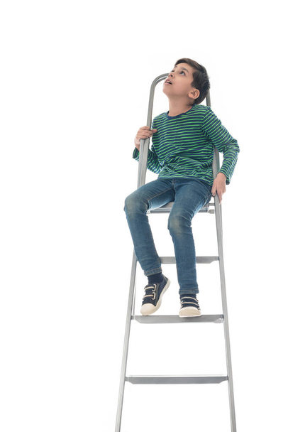 le garçon s'assoit sur une échelle et lève les yeux
 - Photo, image