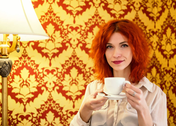 Kızıl saçlı güzel kız bir fincan espresso onu tutuyor - Fotoğraf, Görsel
