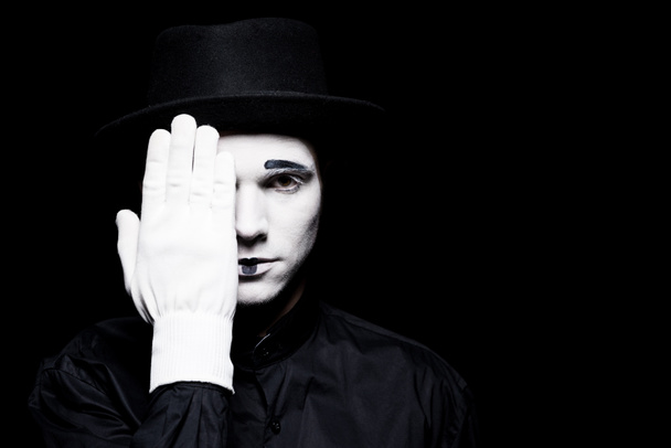 mime covering eye and looking at camera isolated on black - Фото, изображение