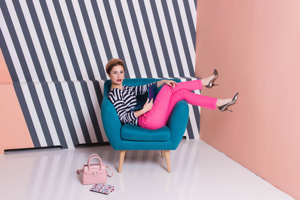 Stylish woman with a laptop in her hands in a striped T-shirt and pink pants, lifestyle, blogger, business, online shopping - 写真・画像