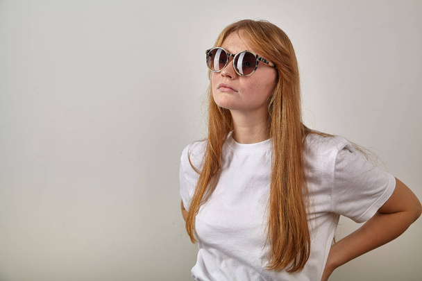 young red-headed woman wearing sunglasses with leopard pattern on earpieces  - Foto, afbeelding