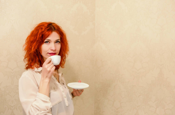 mooi meisje met rode haren houdt een kopje espresso in haar - Foto, afbeelding