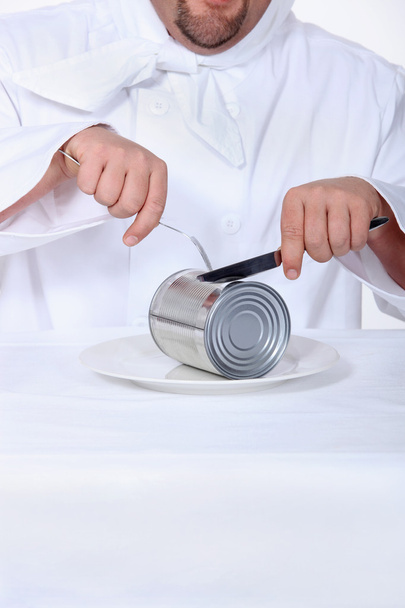 Chef fingindo cortar lata com faca e garfo
 - Foto, Imagem