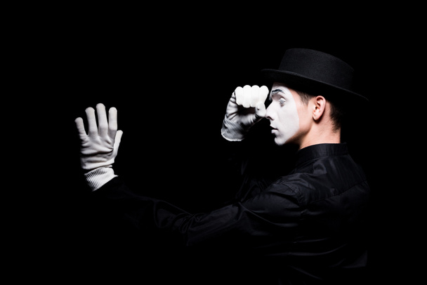 mime pretending looking in spyglass isolated on black - Фото, изображение