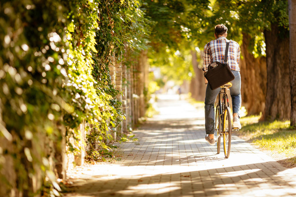 Вид сзади на случайного бизнесмена, идущего на работу на велосипеде
. - Фото, изображение