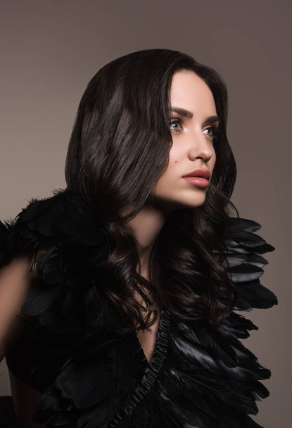 Vertical fashion portrait of young beautiful woman in black. Black hair and black feathers - Fotoğraf, Görsel