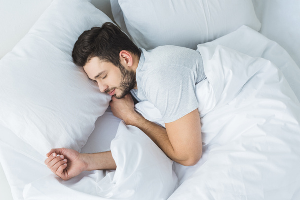 top view of bearded man sleeping on bed in bedroom - 写真・画像