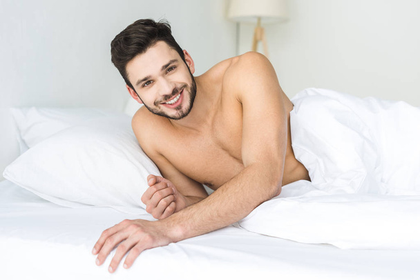 cheerful shirtless man relaxing in bed in the morning - Фото, зображення