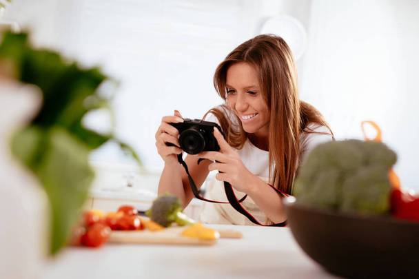 Gyönyörű fiatal nő bevétel fénykép-ból digitális fényképezőgép a blogjában egészséges saláta. - Fotó, kép