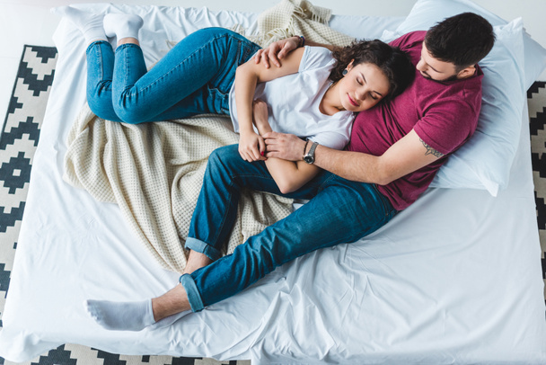 High angle view of young couple lying on bed  - Photo, Image
