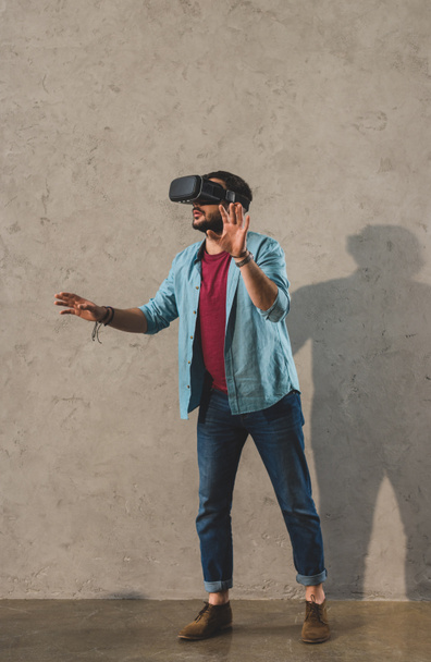 Jeune homme debout devant un mur et utilisant un casque de réalité virtuelle
 - Photo, image