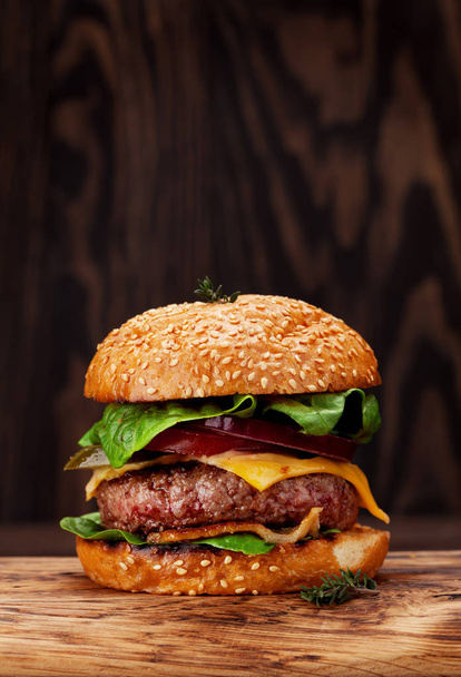 Tasty grilled burger with beef, tomato, cheese, cucumber and lettuce. With copy space - Фото, изображение