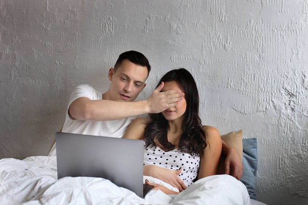Young couple watching tv show, reading a message. Technology & relationship concept. Modern romance troubles. Male & female online dating app. Laptop, chatting, shopping, browsing, surfing. - Φωτογραφία, εικόνα
