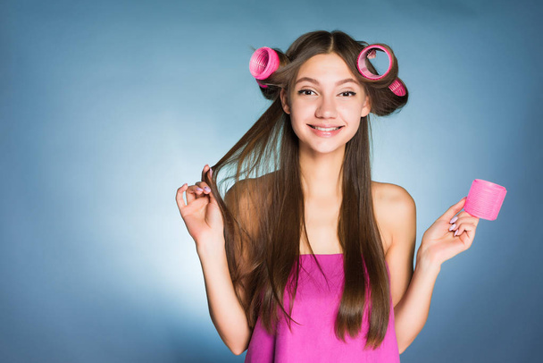 όμορφη νεαρή κοπέλα που κάνει ένα κομψό hairstyle, χρησιμοποιώντας ένα μεγάλο ψαλίδι για μπούκλες, χαμογελώντας - Φωτογραφία, εικόνα