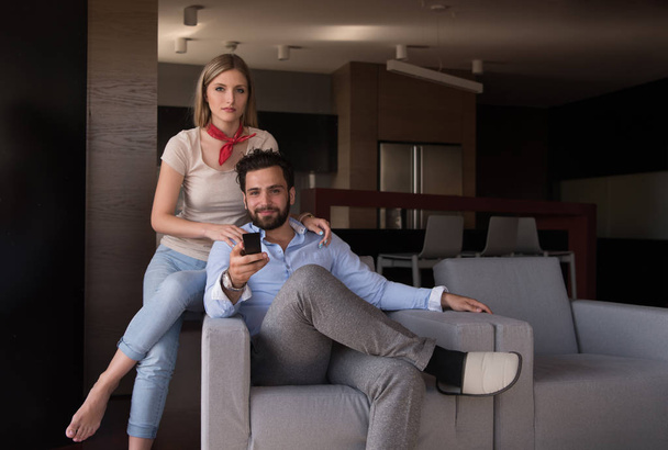 Young couple on the sofa watching television together in their luxury home - Foto, imagen