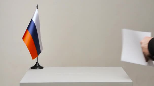 Caixa de voto com bandeira nacional da Rússia. Eleição presidencial em 2018. o eleitor assina e vota. A câmera está fixa
 - Filmagem, Vídeo