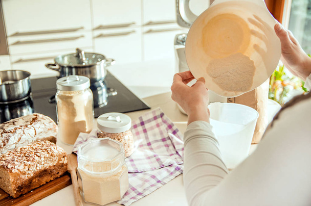 Woman in modern kitchen prepares dough for homemade bread - Фото, зображення