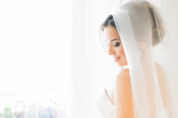Portrait of beautiful bride with fashion veil at wedding morning. - Fotó, kép