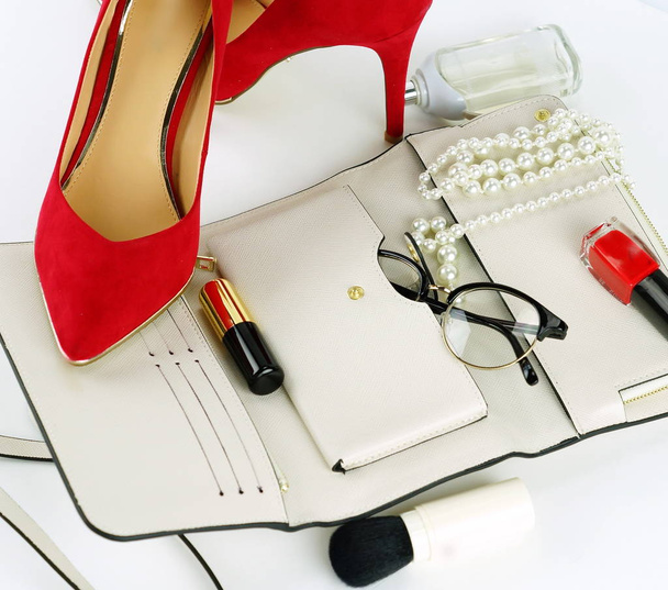 Female fashionable stylish accessories and cosmetics. red shoes with heels, white bag, perfume, glasses, lipstick, red nail polish on a white background. Beauty blog concept. Top view. Flat lay - Foto, Imagem
