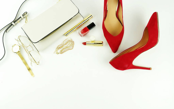 Female fashionable stylish accessories and cosmetics. red shoes with heels, white bag, perfume, glasses, lipstick, red nail polish on a white background. Beauty blog concept. Top view. Flat lay - Photo, Image