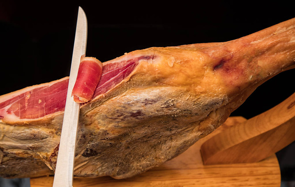 Primo piano di un coltello che taglia un prosciutto spagnolo serrano
 - Foto, immagini