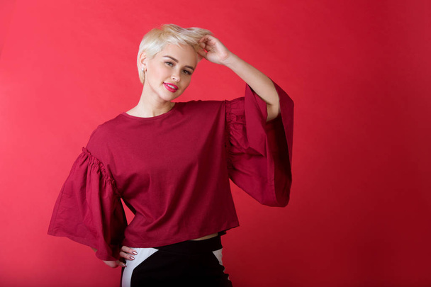 beautiful young girl with snow-white smile and healthy teeth with short hairdo on red background - Foto, Imagem