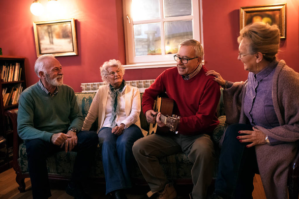 Старшие люди делают партии улыбаясь и наслаждаться вместе дома
 - Фото, изображение