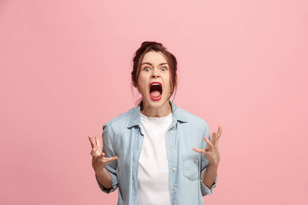 The young emotional angry woman screaming on pink studio background - Photo, Image