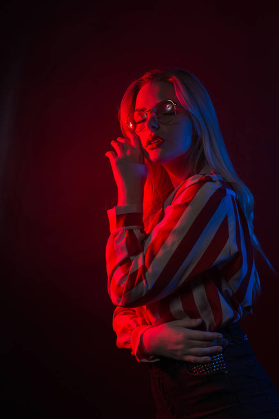 Aistillinen blondi nainen lasit poseeraa punainen ja sininen studio
  - Valokuva, kuva