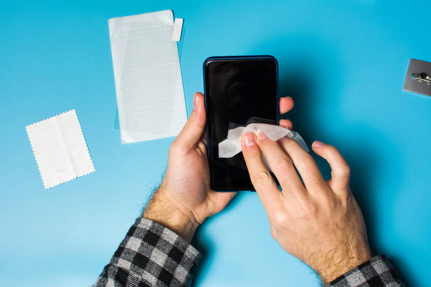 Homem de limpeza tela do telefone para aplicar vidro de proteção
 - Foto, Imagem