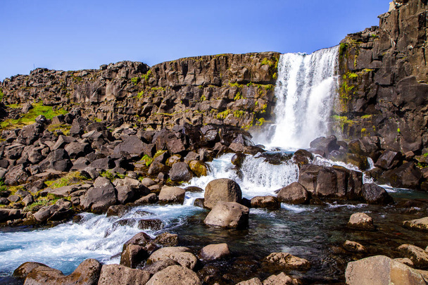 Stone precipice and waterfall in the national park. Thingvellir in Iceland 12.06,2017 - Zdjęcie, obraz