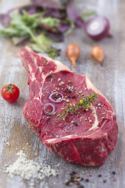 Raw T-bone Steak prepared for grill over on a aged wooden background, top view - Fotó, kép