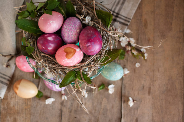 Easter eggs in nest with napkin on raw wooden table - Zdjęcie, obraz