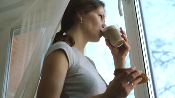 Młoda dziewczyna z piegami cappuccino picie i jedzenie ciasto - Materiał filmowy, wideo