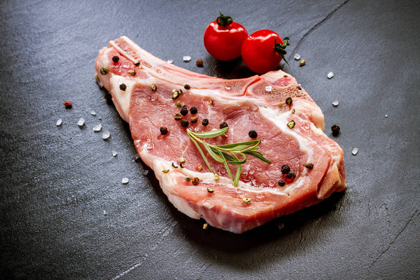 Raw veal cutlet at black slate plate - 写真・画像