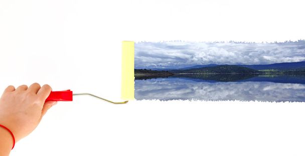 eine Person malt mit einem Rollerpinsel eine Seenlandschaft auf eine weiße Wand - Foto, Bild
