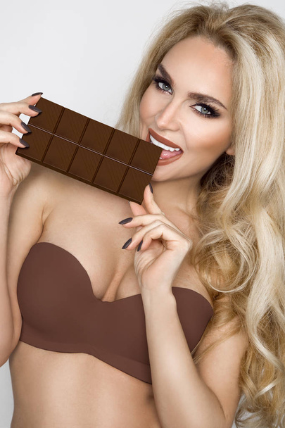 Hermosa, rubia sexy, comiendo chocolate sensualmente
. - Foto, Imagen