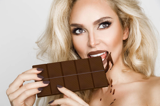 Beautiful, sexy blonde, sensually eating chocolate. - Photo, Image