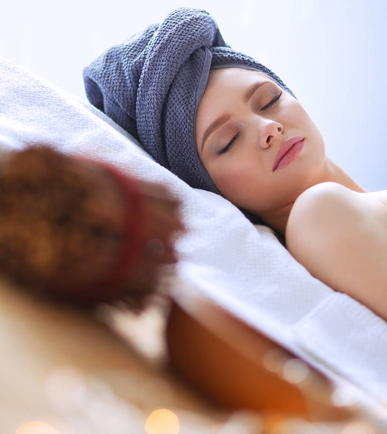 Young woman lying on a massage table,relaxing with eyes closed - Фото, изображение