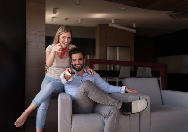 Young couple on the sofa watching television together in their luxury home - Photo, Image