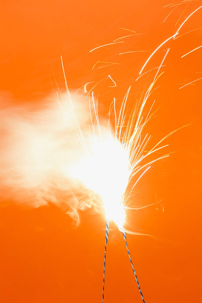 A narancsszínű háttér-két égő tűzijáték - Fotó, kép
