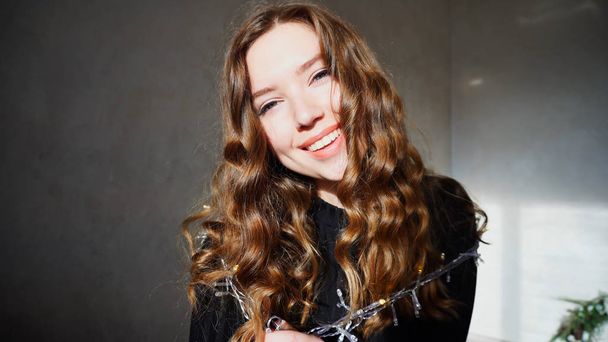 Fiatal nő mosolyogva, látszó-on fényképezőgép-göndör haj - Fotó, kép