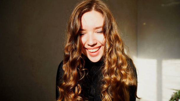Genç kadın kıvırcık saçlı kameraya bakarak gülümseyen, - Fotoğraf, Görsel