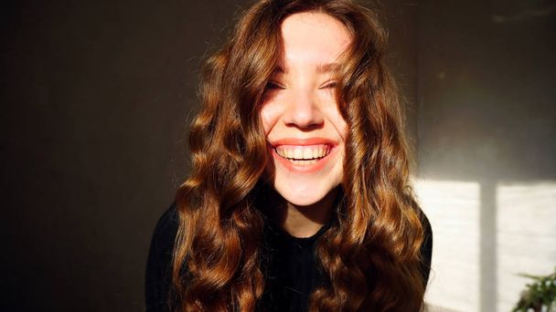 Fiatal nő mosolyogva, látszó-on fényképezőgép-göndör haj - Fotó, kép