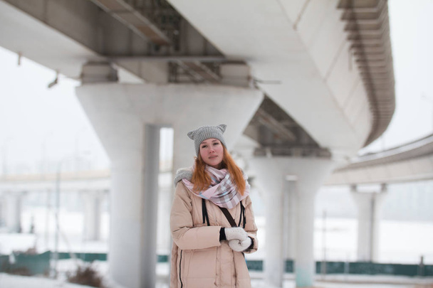 Retrato de mujer joven se encuentra bajo un gran puente, moderna ciudad de invierno
 - Foto, imagen