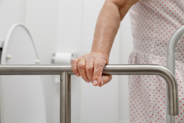 Femme âgée tenant la main courante dans les toilettes
. - Photo, image