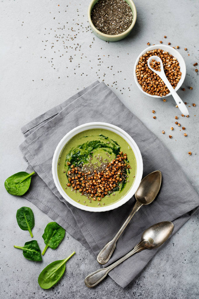 Useful smoothies from spinach with buckwheat flakes in ceramic bowls on gray concrete table background. Selective focus. Top view. Copy space. - 写真・画像