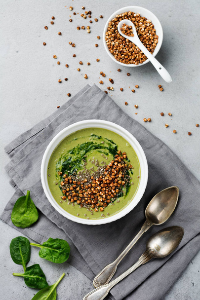 Useful smoothies from spinach with buckwheat flakes in ceramic bowls on gray concrete table background. Selective focus. Top view. Copy space. - Fotoğraf, Görsel