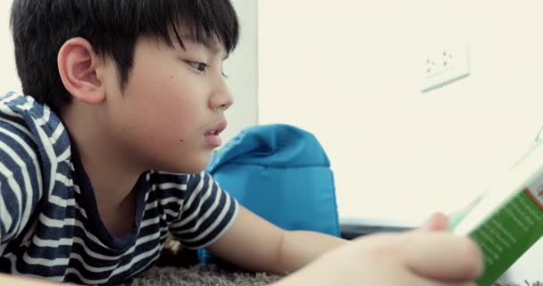 Asiatique pré adolescent repos sur le sol et la lecture de dessins animés livre .Be visage lisse
. - Séquence, vidéo