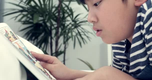 Asiático pré adolescente descansar no chão e ler desenhos animados livro .Be rosto liso
. - Filmagem, Vídeo